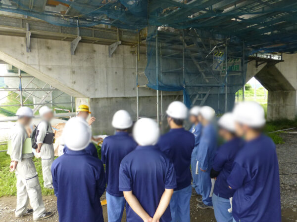 高校生の現場見学会。生徒さん達に施工図と工事の状況を見せながら説明している様子を近場で撮影した画像。
