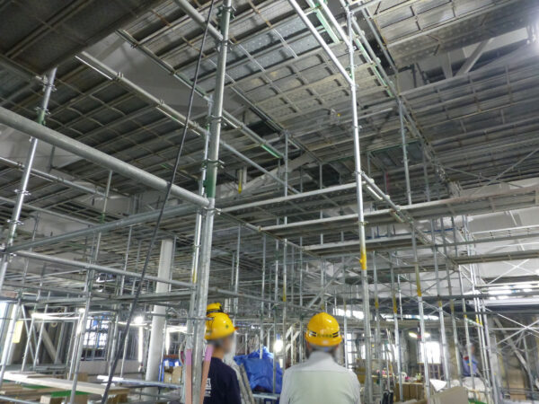 2日目中学生の職業体験。建物内の2階の天井を施工している様子を見ている画像