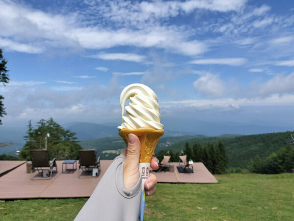 蓼科牧場ゴンドラに乗って頂上へ。頂上にある飲食店で生乳ソフトクリームを景色の綺麗な背景といっしょに撮影した画像。