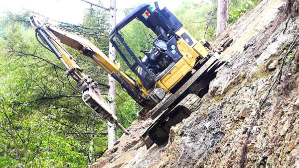 無人化施工（ラジコン操作）。セーフティークライマー（小さいショベルカーの先端に破砕用のドリルが付いている重機）の画像。無人状態で動作している様子