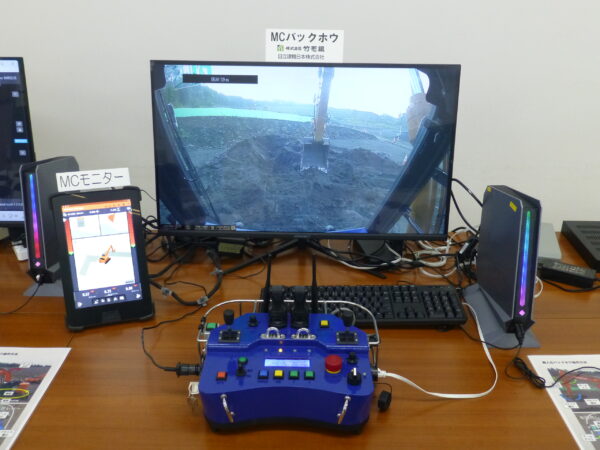 無人化施工機械操作体験会。浅間出張所内にある遠隔操作室。バックホウの操縦用のコントローラとモニター