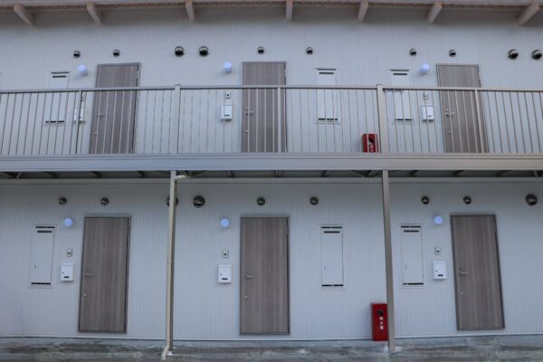 共同住宅の外観。ホワイト系で統一されたドアと外壁、屋根。