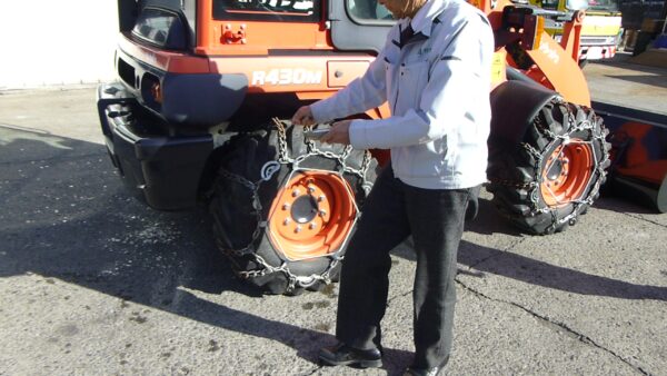 納車式にてお清めの塩を重機周辺に撒いている様子の画像