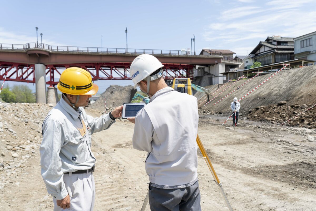 土木工事現場でタブレット画面を確認する作業員。